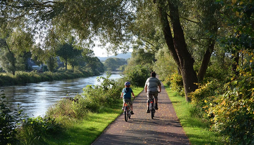 otec a syn bicyklujú po cykloceste vedľa rieky