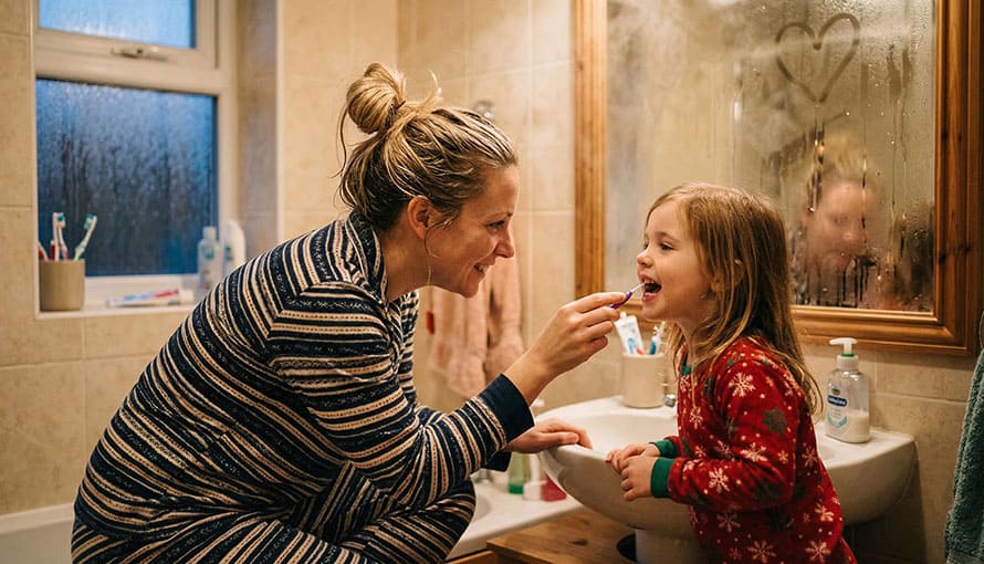 mama dočisťuje dieťaťu zuby medzizubnou kefkou